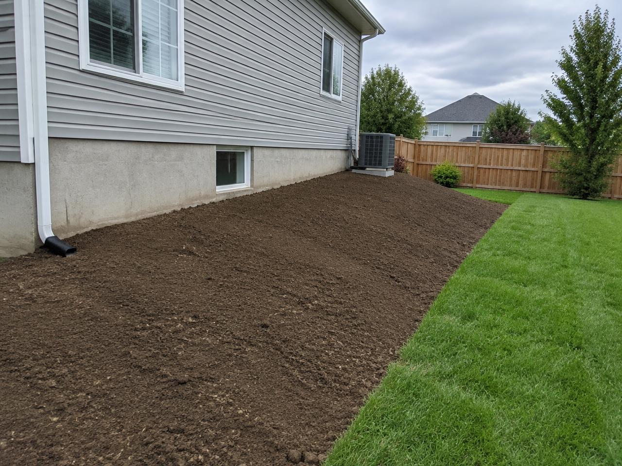 Regraded soil sloping away from a home foundation in Southern Iowa